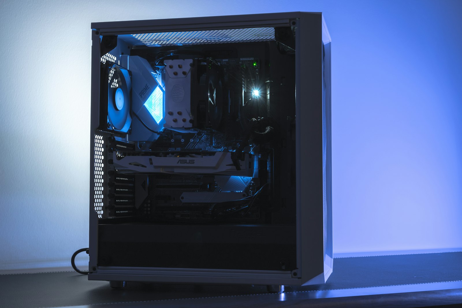 Gaming PC tower with a glass side panel showing the graphics card and cooling fans lit in blue